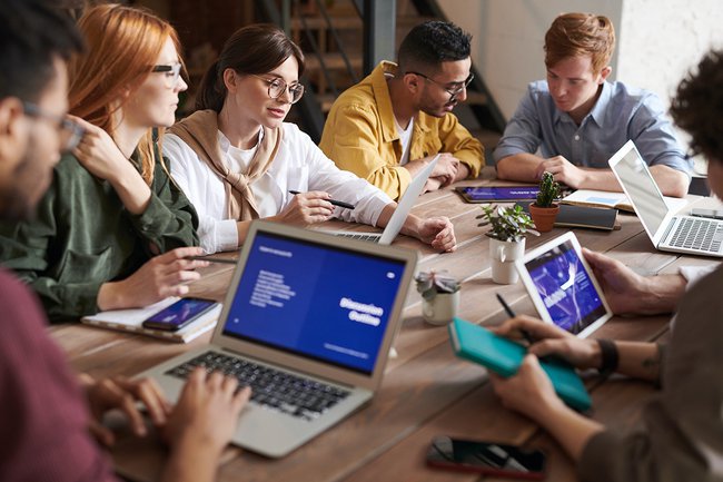 GenZ und der Kapitalmarkt – Symbolfoto: junge Menschen mit Laptops an einem Tisch